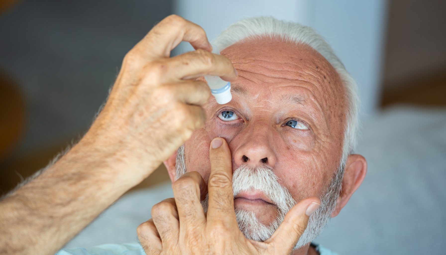 Person applying post-operative eye drops after cataract surgery